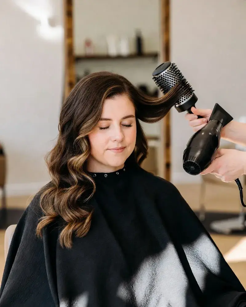 Stylist finishing a blowout with a round brush